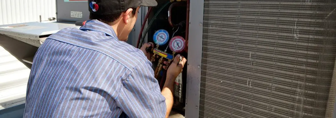 HVAC technician servicing a condenser unit in Burton