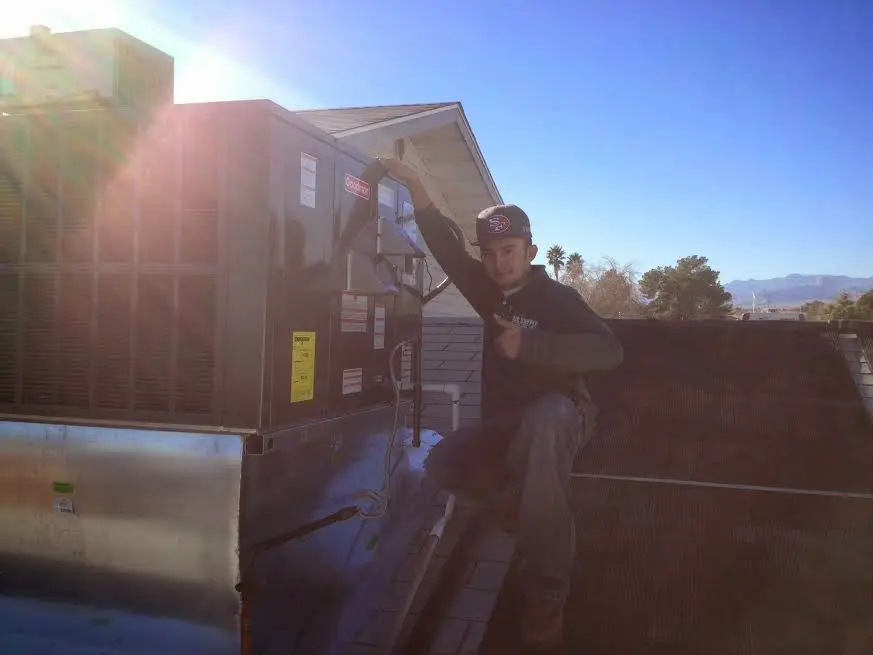 HVAC technician performing Air Duct Repair on a rooftop unit in Burton